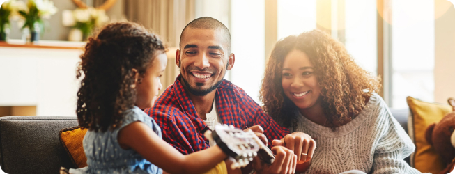 family on couch with dad playing guitar while mom and child watch